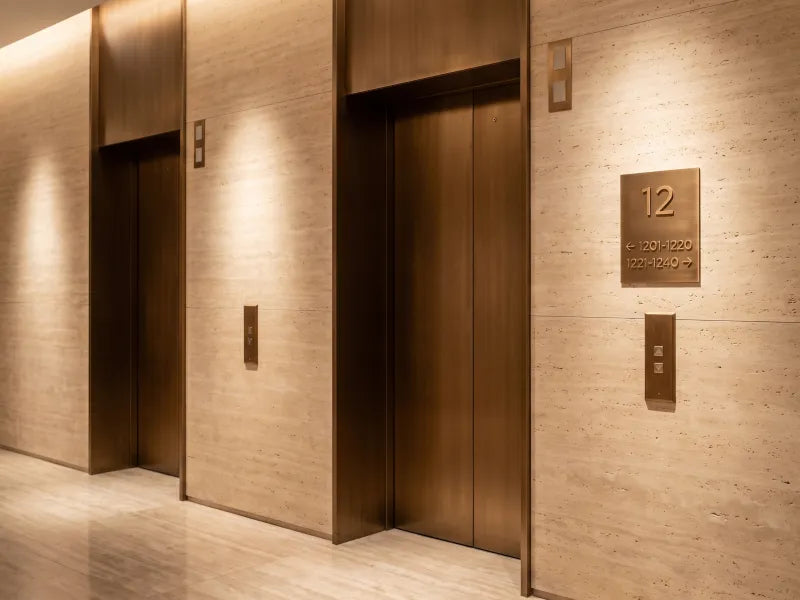 Illustration: bronze floor directory with room ranges beside hotel elevator doors